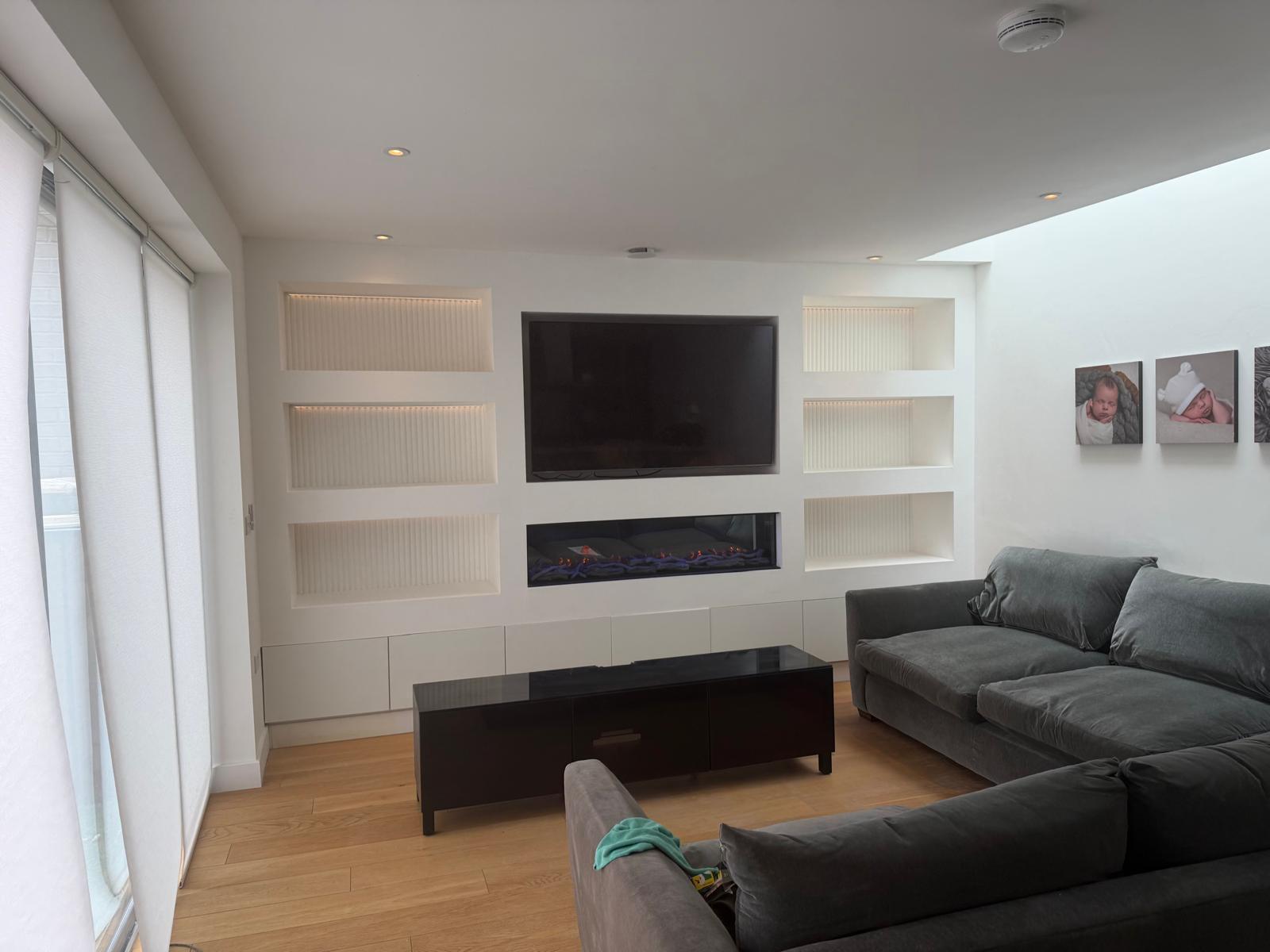 Finished living room media wall with recessed lighting, feature fire and integrated electrical installation